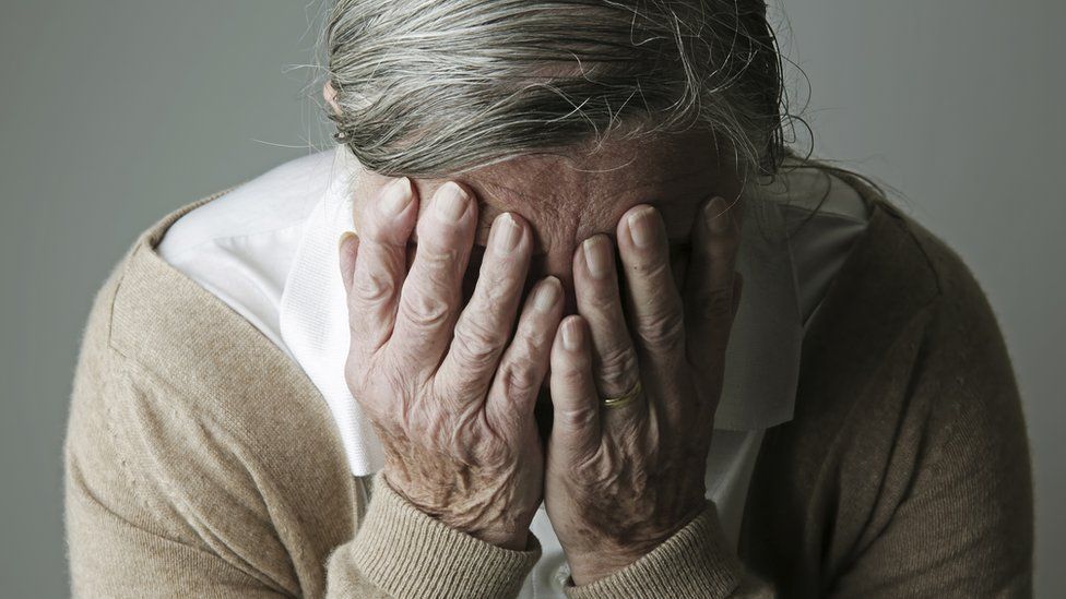 Older woman holds her head in her hands