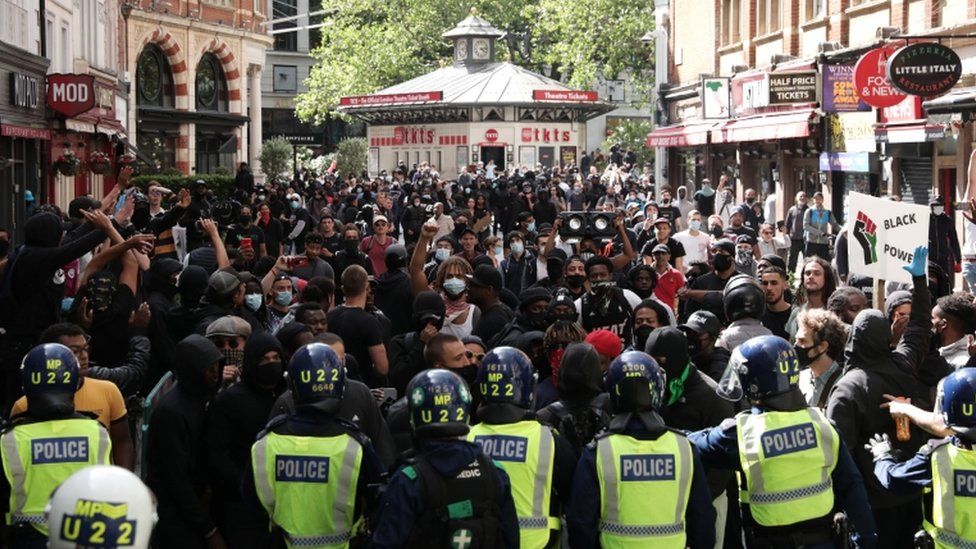 Police form a barrier in front of anti-racist protesters near Leicester Square