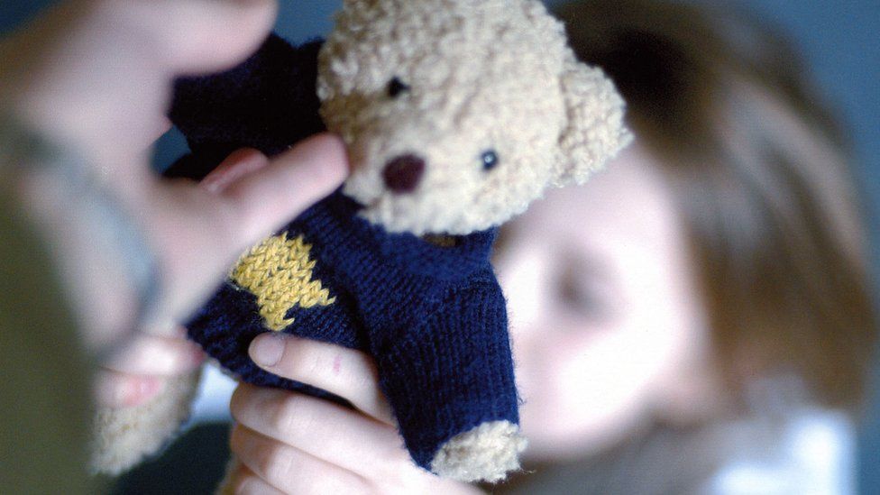 child being handed teddy
