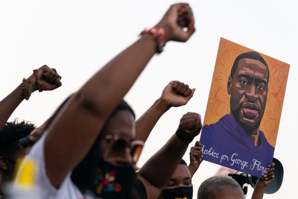 People raise their fists and hold a portrait of George Floyd during a rally following the guilty verdict the trial of Derek Chauvin on 20 April 2021, in Atlanta, Georgia
