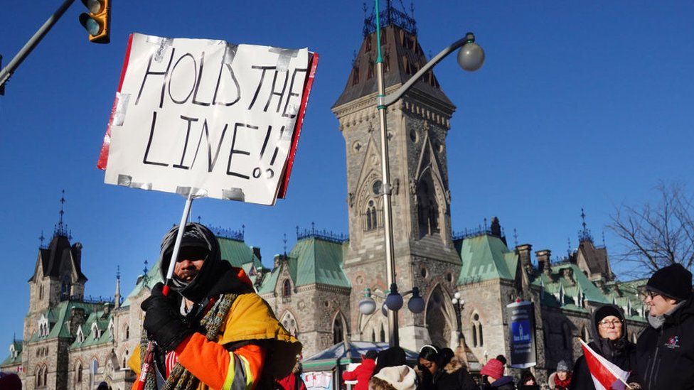 Водители грузовиков и их сторонники блокируют улицы во время акции протеста против мандата на вакцинацию возле здания парламента 15 февраля 2022 года в Оттаве, Онтарио, Канада