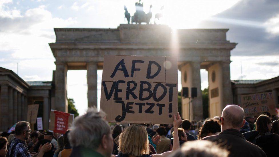 A protester holds a placard reading "AfD ban now!' during a rally in Berlin, 5 May 2024.