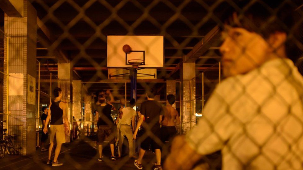 Youngsters in China play basketball in a court beneath a road