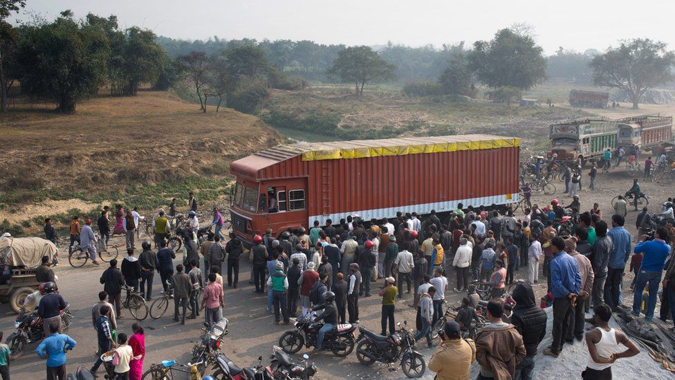 Nepalese and Indian bystanders look on as cargo trucks pass through the India-Nepal border at Birgunj, some 90kms south of Kathmandu.
