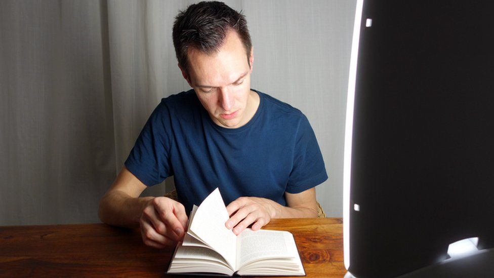 Man reading a book with a light