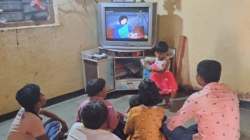Children sit in front of a TV