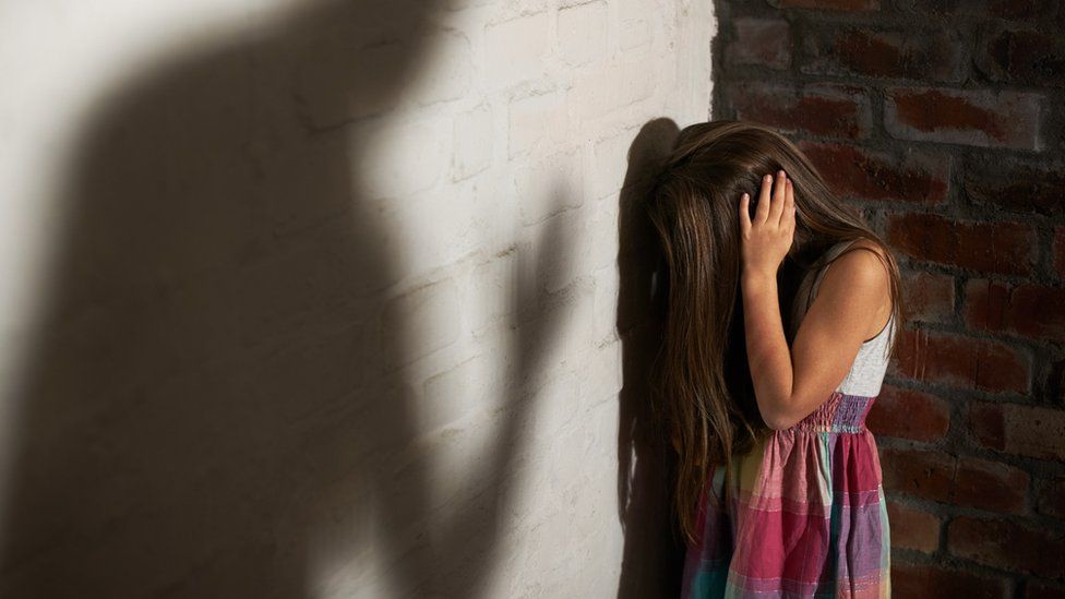 Girl in corner with shadow towering over her