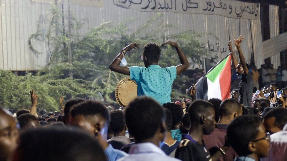 Two people sitting one others' shoulders at a sit-in at the military HQ in Khartoum, Sudan - Sunday 7 April 2019