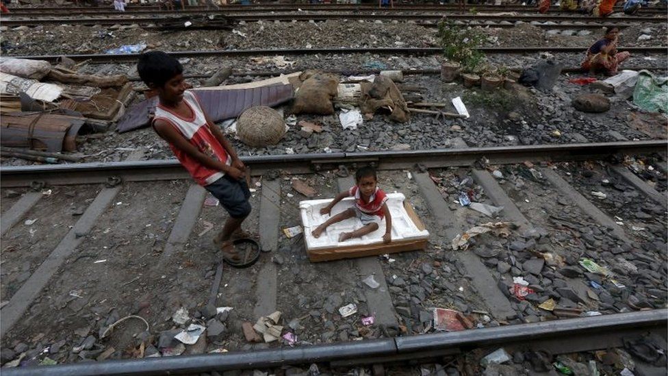 Ratan Mandal, 10, pulls three-year-old Bubai Tati, as he sits on a broken box on a railway track in a slum area in Kolkata, India, March 13, 2016.