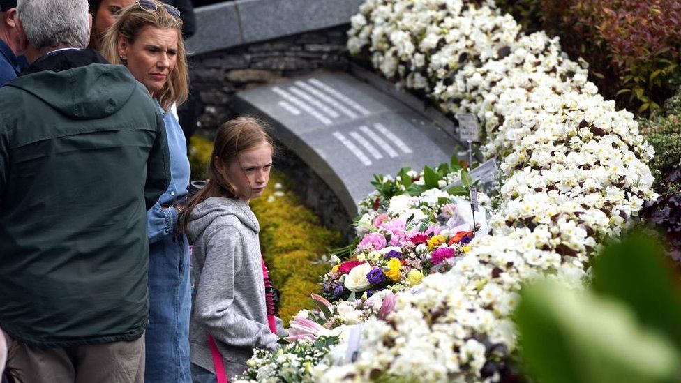 People gathered at the monument following the service to view the floral tributes left to the victims