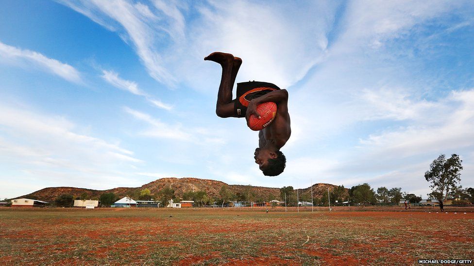 A young footballer performs a backflip during a training session in Alice Springs