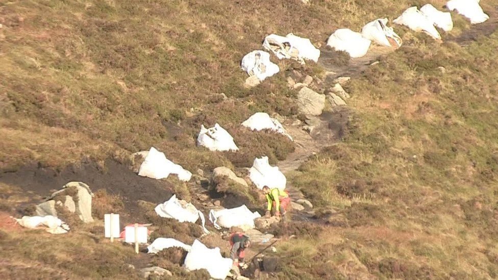 Large bags of stone and other materials used in the repair sit along the path on Slieve Gullion