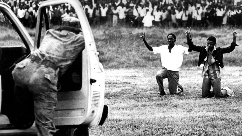 Soweto youths kneeling in front of the police holding their hands in the air showing the peace sign on June 16, 1976, in Soweto, South Africa.