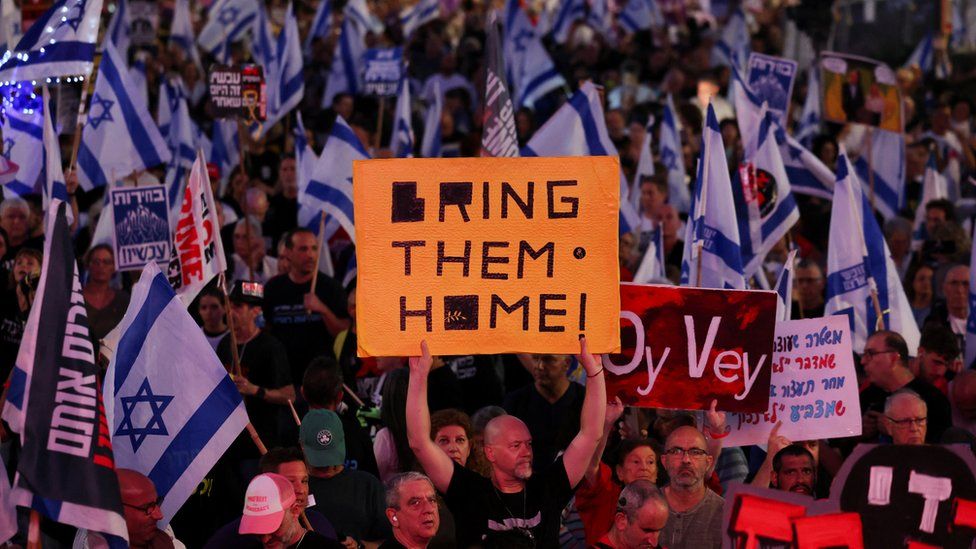 Dozens of protesters waving Israeli flags and placards in Tel Aviv calling for hostages to be returned home