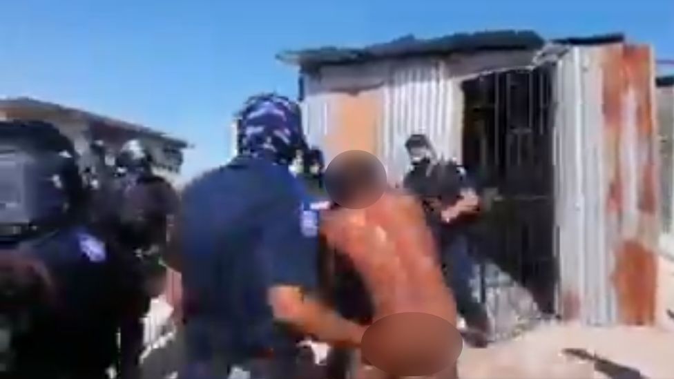 Police officers prevent a naked man from re-entering the house they've forced him out of