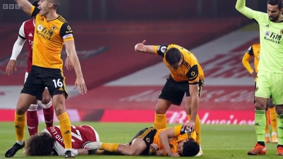 Raúl Jiménez lying on the floor of the pitch after suffering the injury, as other players wave over help