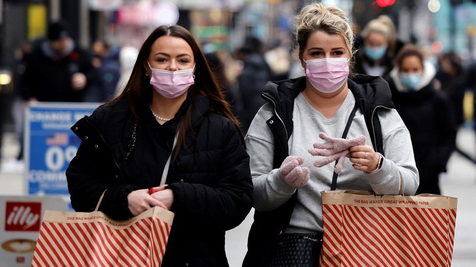 Shoppers wearing face coverings to help combat the spread of Covid-19, carry Primark bags as they walk along Bond Street in London on December 21, 2021