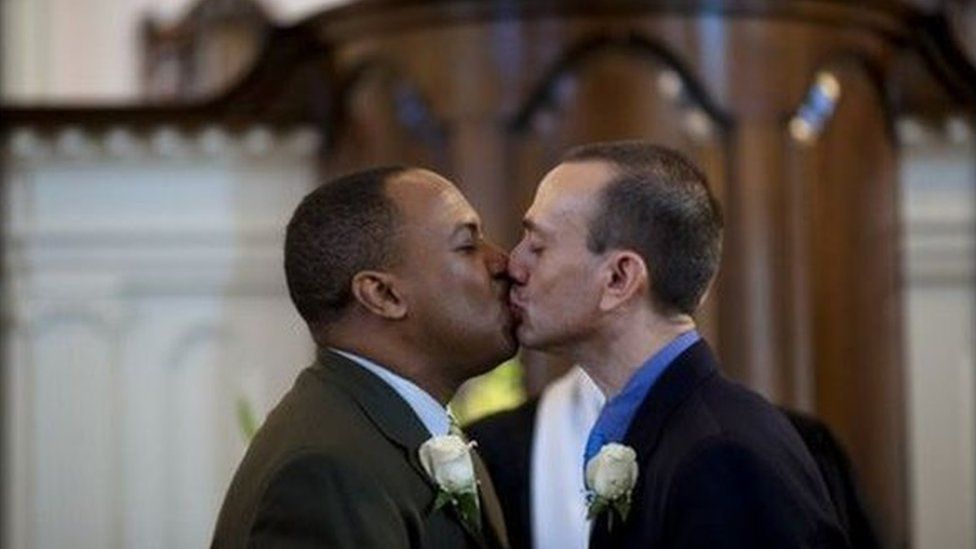 Two men kissing at altar