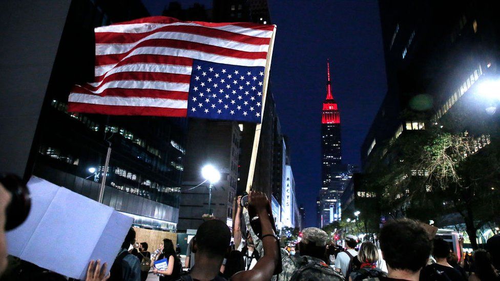 The Empire State Building illuminated in red as protesters march