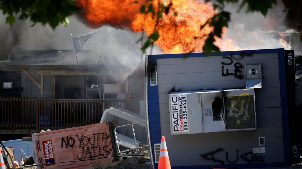 A portable trailer on the site of the King County Juvenile Detention Center is engulfed in flames