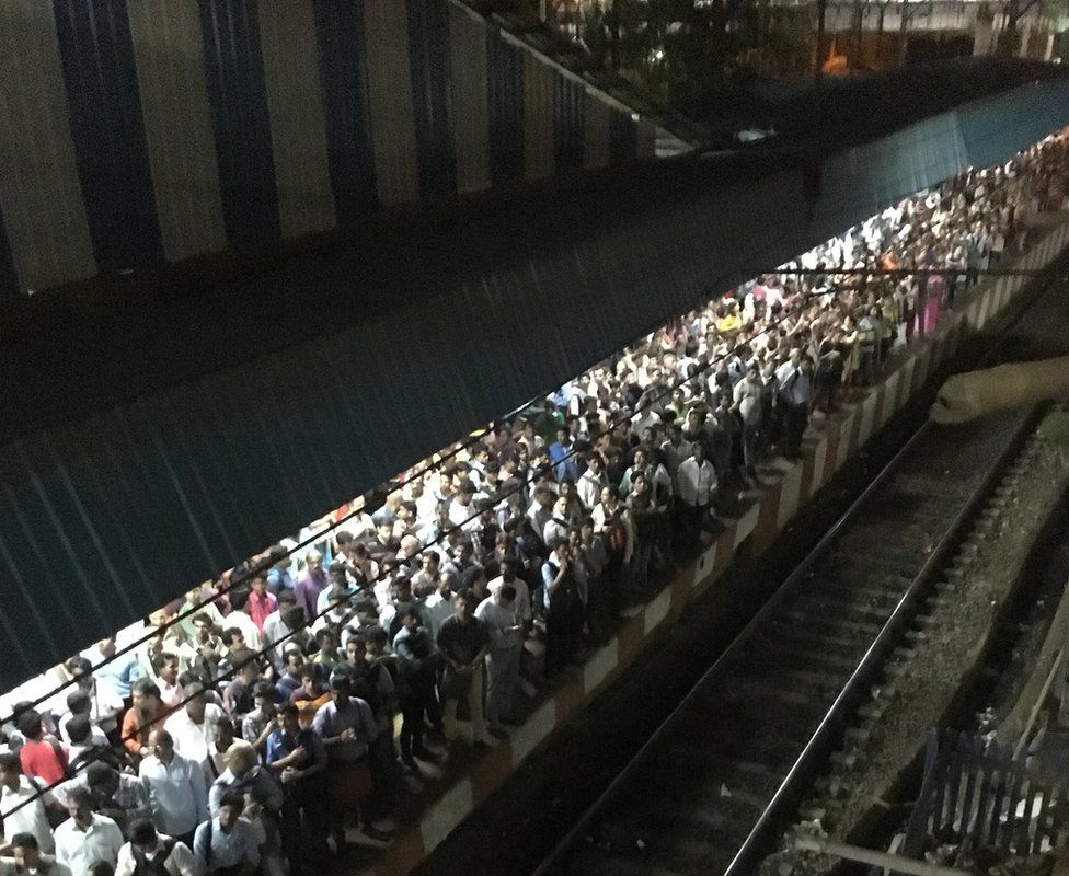 Passengers wait to board a local train in Mumbai