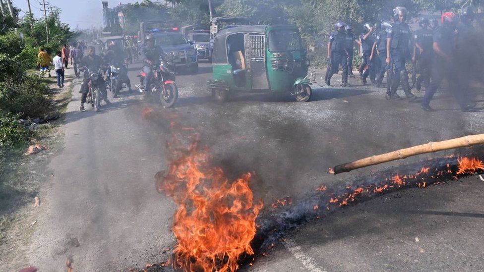 Motorists watch fire on road outside Dhaka in Bangladesh during protests