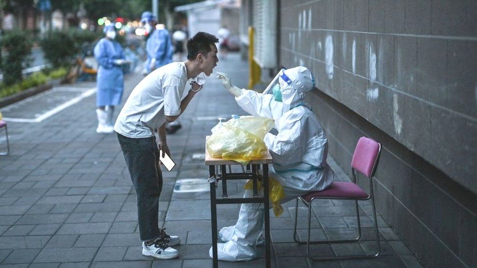 A health worker takes a swab sample from a man to test for the Covid-19 coronavirus in the Jing'an district of Shanghai on July 5, 2022.