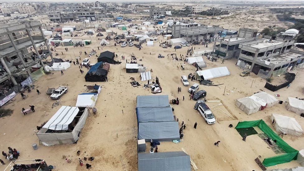 A photo overlooking Al-Mawasi. People and tents can be seen in the foreground