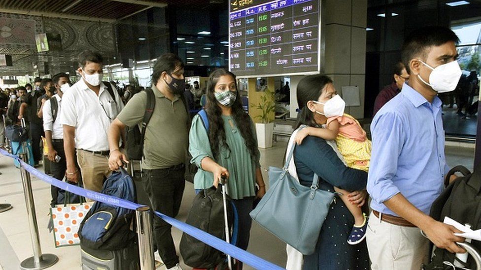 Pasajeros hacen cola en el exterior de un aeropuerto de la India