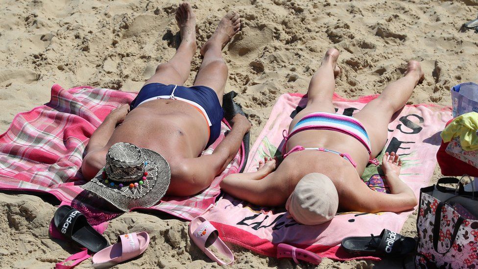 People sunbathe as they enjoy the warm weather on Boscombe beach in Dorset