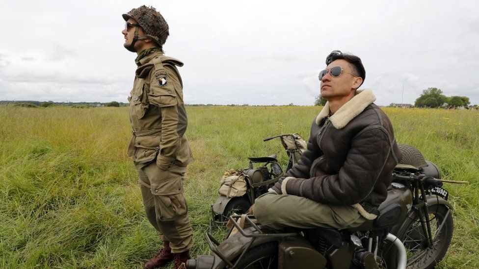 Parachutists watch others drop to the ground