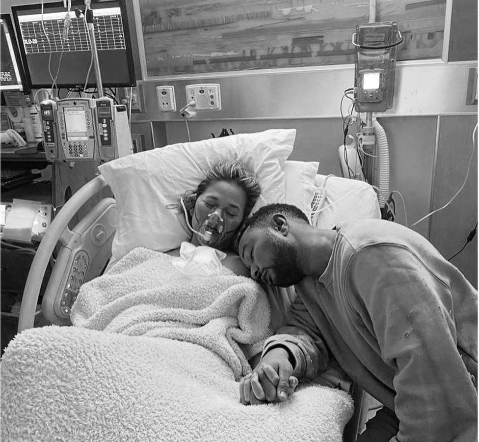 Chrissy Teigen is comforted by her husband in hospital