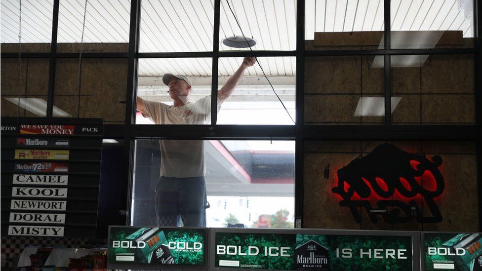 Wesley Jacobs measures a space for plywood as he helps board up the windows on a business before the possible arrival of Hurricane Laura on August 25, 2020