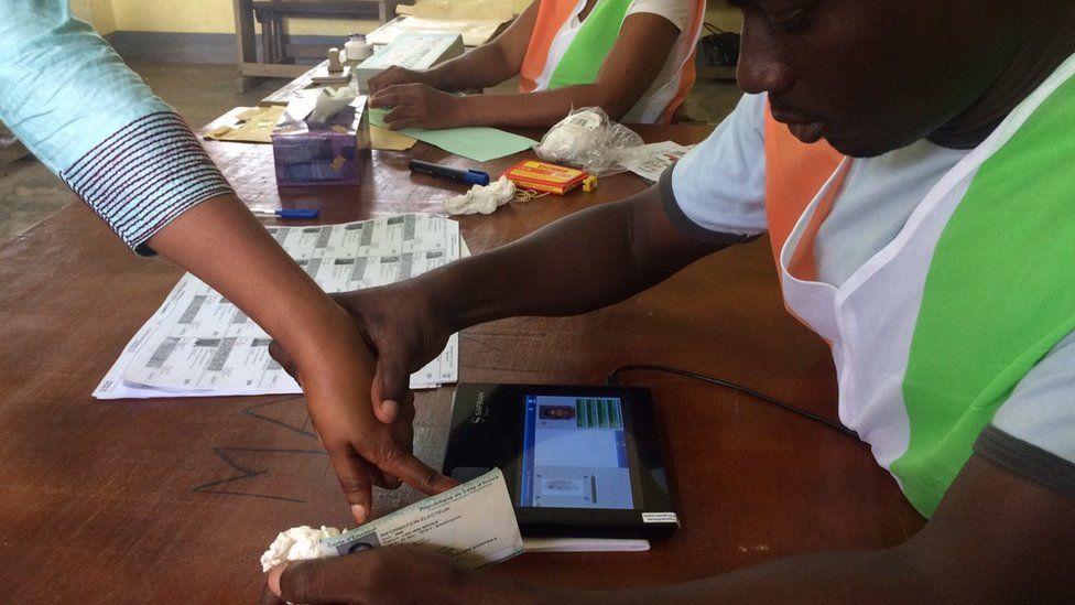 Election official helping a voter use the biometric system