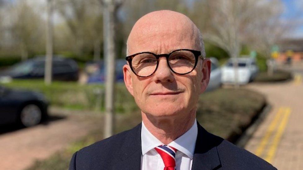 Dr Michael Marsh wearing round black glasses standing outside looking into the camera