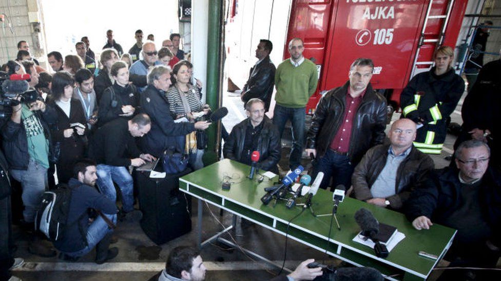 Hungarian Prime Minister Viktor Orban (standing 3R) listens to a journalist's question at the fire station headquarters in Ajka, 140km (87 miles) west of Budapest on 9 October 2010