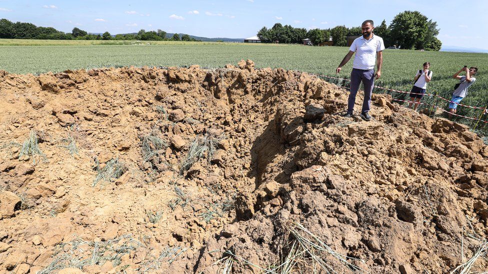 People look at a crater in a field in Ahlbach, Germany, 24 June 201