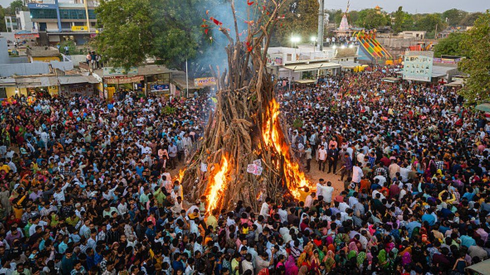 Devotees perform ''Holika Dahan'' in a village near Gandhinagar, the capital of Gujarat, on March 24, 2024. The village is maintaining its 700-year-old tradition. A Holi fire, towering at 35 feet and built within a 30-meter circumference using 200 tons of wood, is resulting in flames that soar to impressive heights. (Photo by Saurabh Sirohiya/NurPhoto via Getty Images)