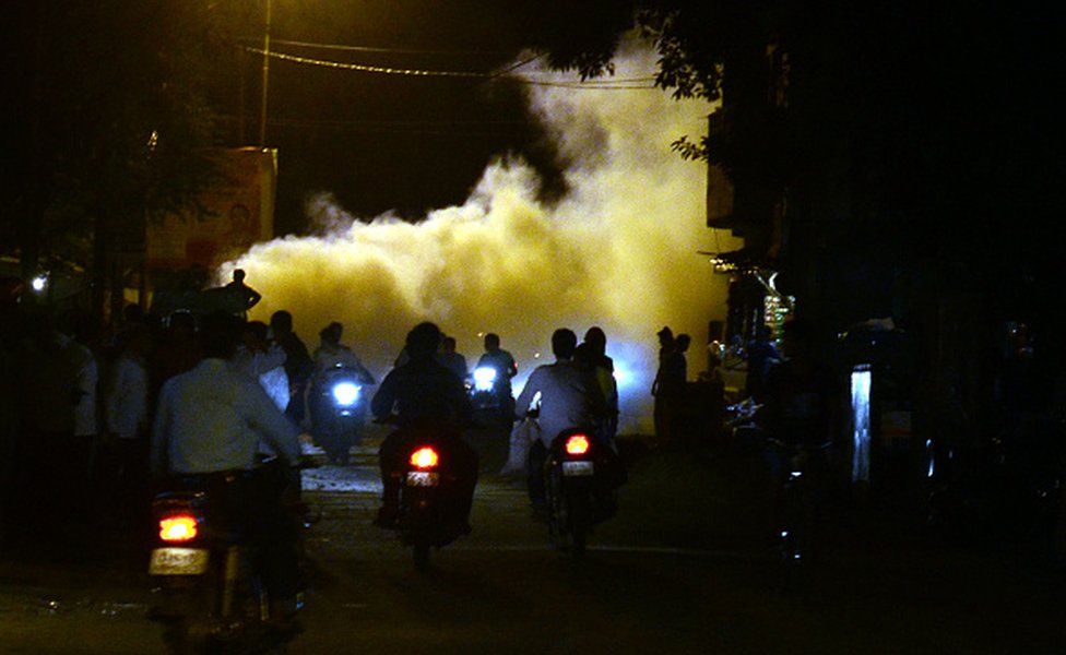 Indian people pass through smoke from fumigation in a busy old street of Allahabad on September 27,2016.