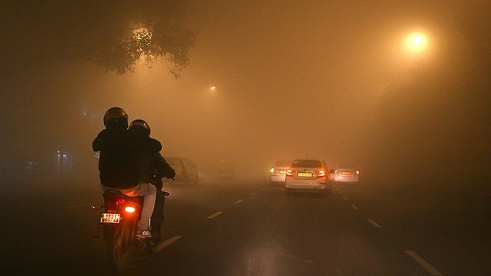 Vehicles travel through dense fog on a cold winter morning in New Delhi on December 27, 2023