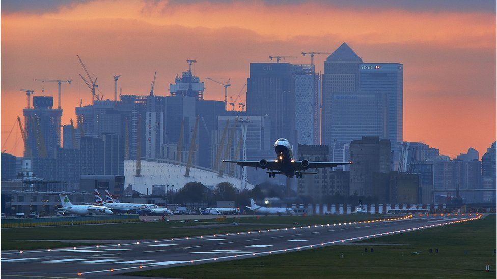 Plane takes off from London City Airport with Canary Wharf in the background