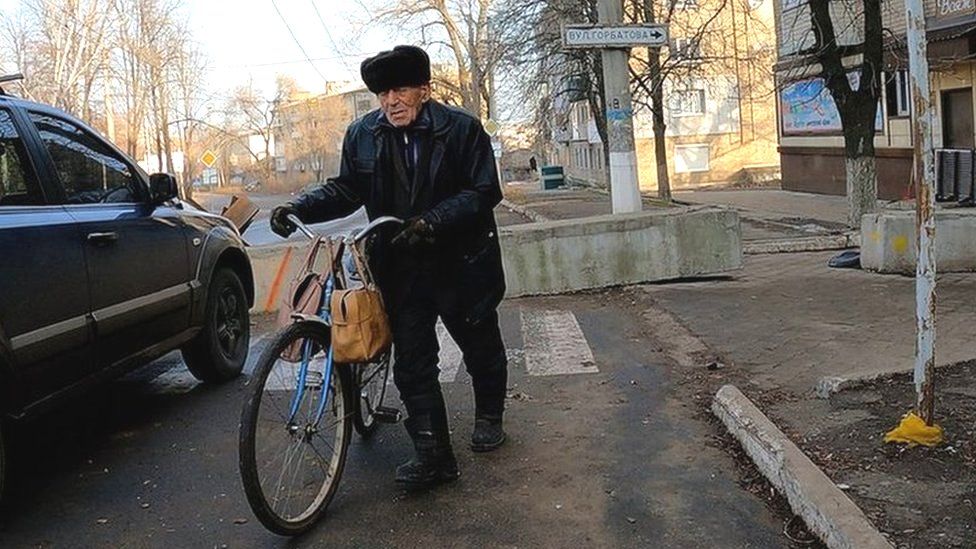 Older man pushes bicycle on street in Bakhmut