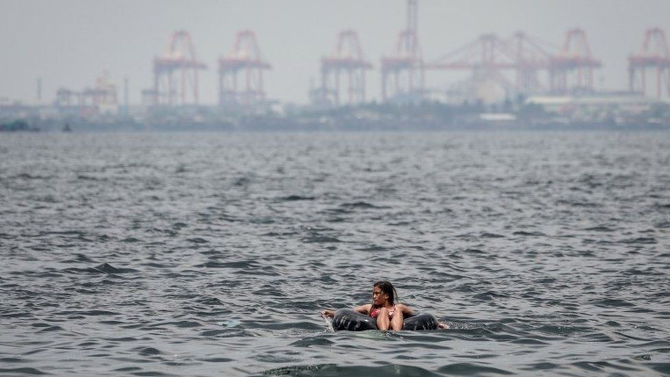 A woman floats on an inner tube of a rubber wheel on Easter Sunday at Manila Bay, Pasay City, south of Manila, Philippines, 01 April 2018