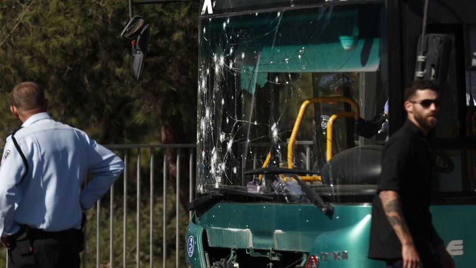 Israeli security forces stand near a bus damaged by an explosion in Ramot Junction, Jerusalem (23 November 2022)