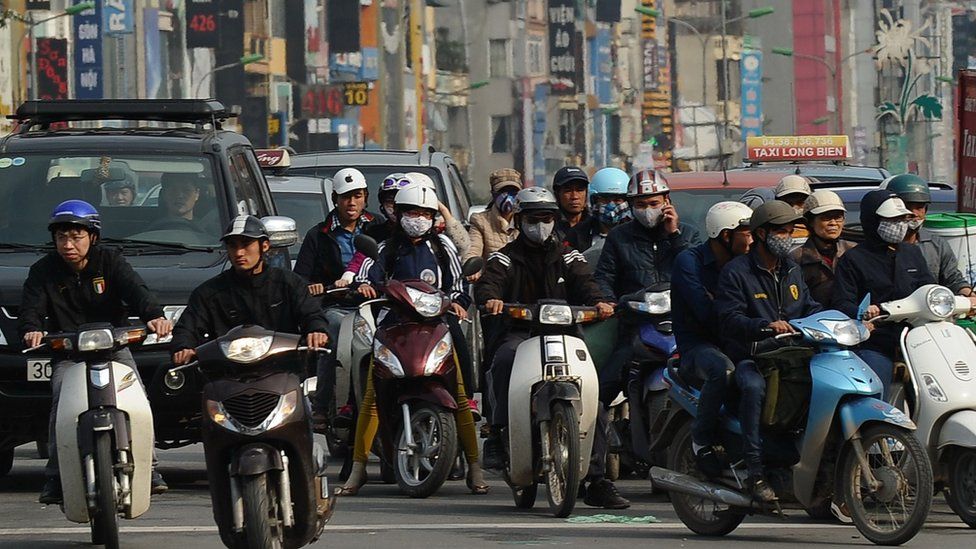 Motorcyclists ride through an intersection in downtown Hanoi