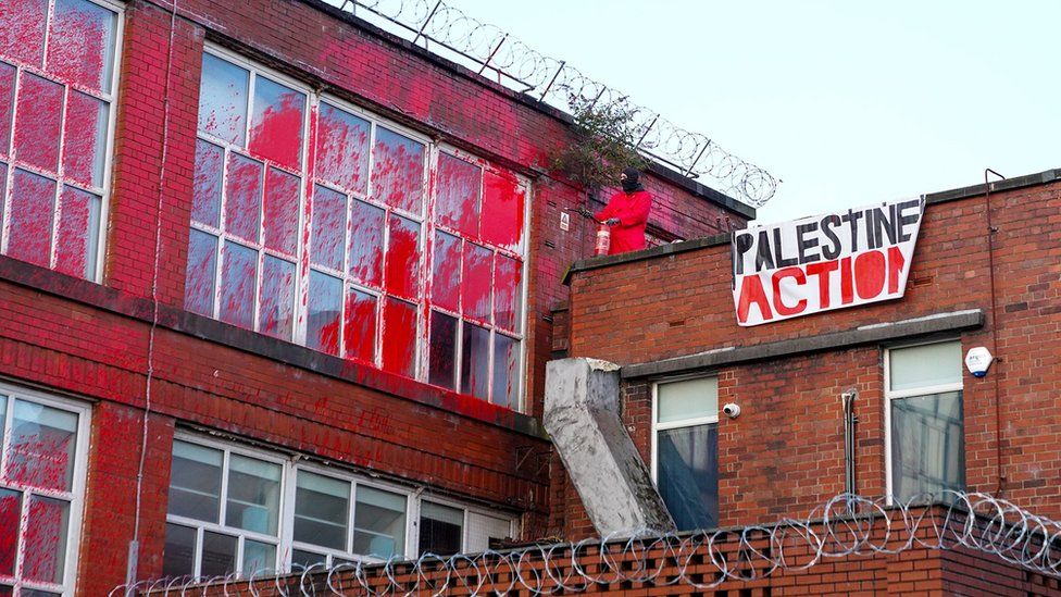 Protester spraying red paint from factory roof