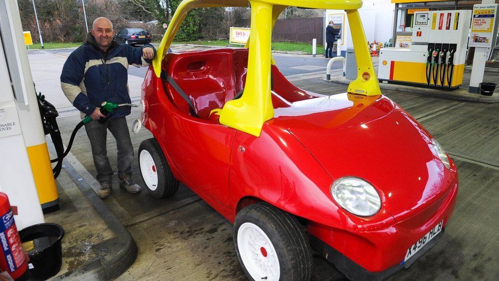John Bitmead filling up the adult-sized Little Tikes toy car with petrol