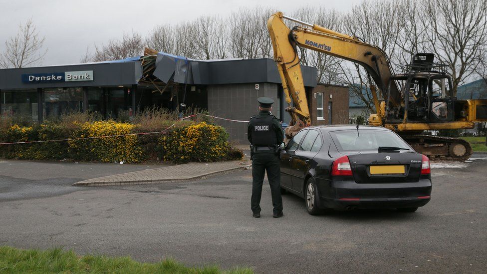 A police officer and the digger at the Danske Bank branch in Newtownabbey