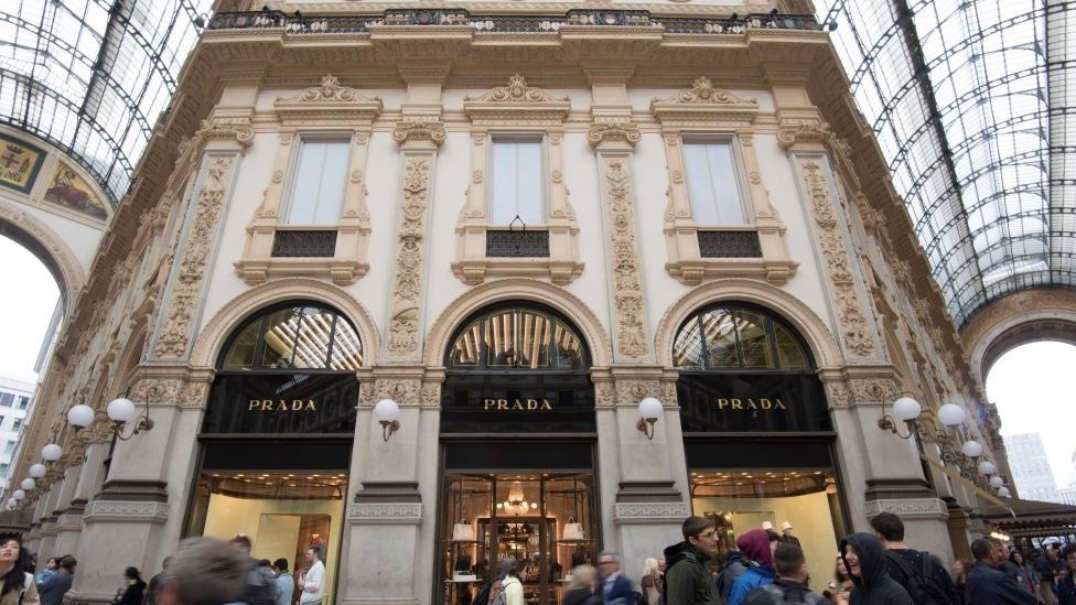 ourists and Milanese walk past luxury fashion shop Prada in the Vittorio Emanuele II luxury Gallery in the center of Milan