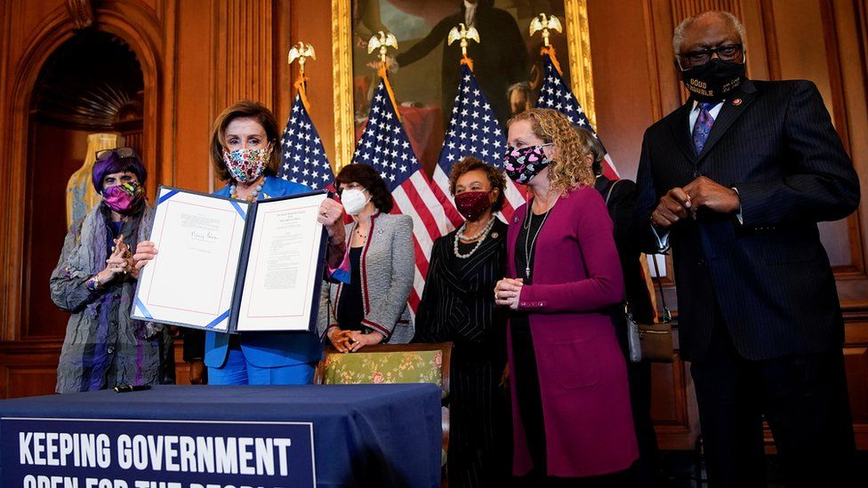 U.S. House Speaker Nancy Pelosi (D-CA) is flanked by members of the House Democratic Caucus as she holds the continuing resolution she signed to avoid a U.S. government shutdown during a bill enrollment ceremony on Capitol Hill in Washington, U.S., September 30, 2021